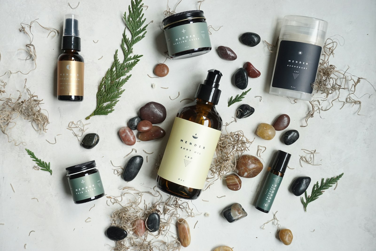 Herbal skincare and body products arranged among stones and dried botanicals